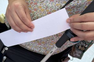 A visually impaired visitor explores a Braille quote with her fingertips