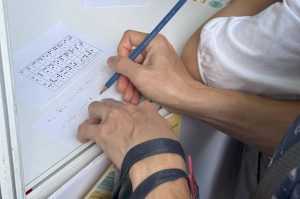 An elderly visitor tries her hand at decoding quotes using the Unified English Braille (UEB) chart