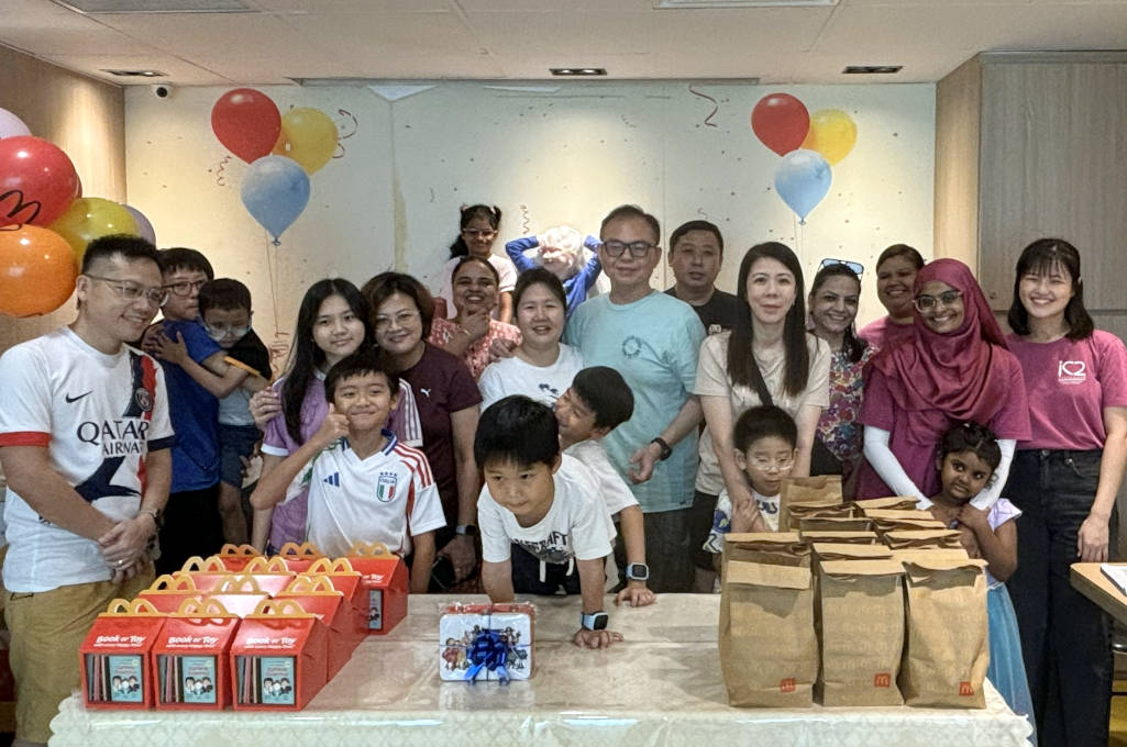 Group photo of children, parents, and teachers celebrating the closing of a fun Kids’ Day event at McDonald’s, all smiling and posing together.