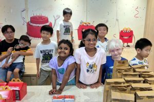 Children standing behind a table filled with McDonald’s goodie bags and meals, smiling and excited.