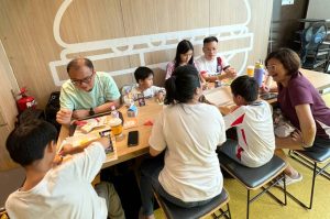 Children and adults sitting together around a table at McDonald’s, enjoying food and activities during a Kids’ Day event.