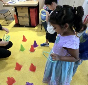 Children smiling and tossing rings onto small cones in a colorful ring toss game.
